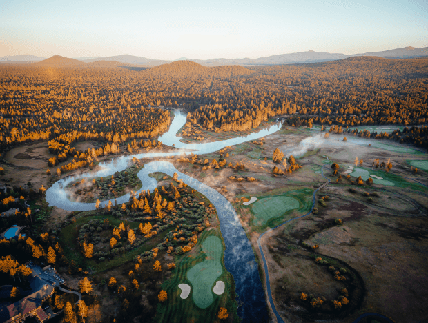 overview of crosswater golf course with yellow trees and a winding river and blue skys