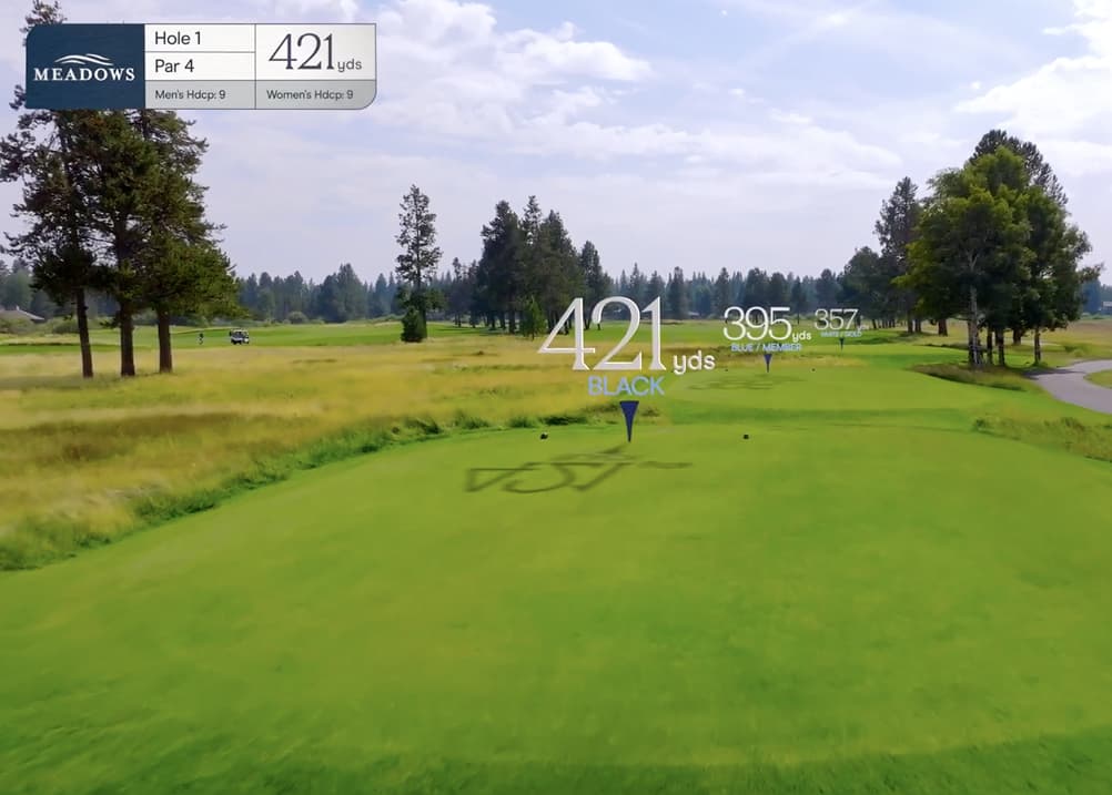 Aerial tee box view of Meadows Golf Course Hole 1, a 421-yard par 4 with an open fairway, light rough, and trees lining both sides.