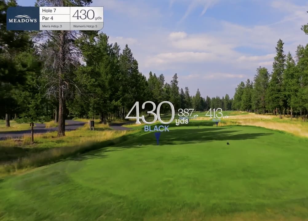 Aerial tee view of Meadows Golf Course Hole 7, a 430-yard par 4 with a slightly narrowing fairway framed by tall pines and shaded rough.
