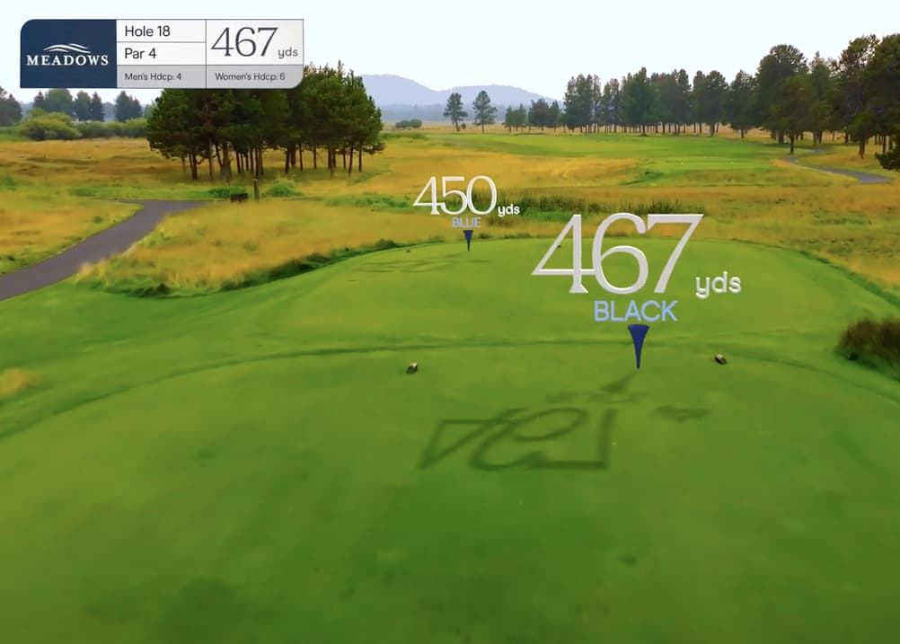 Aerial tee view of Meadows Golf Course Hole 18, a 467-yard par 4 with an open fairway stretching toward distant hills and bordered by natural grassland.