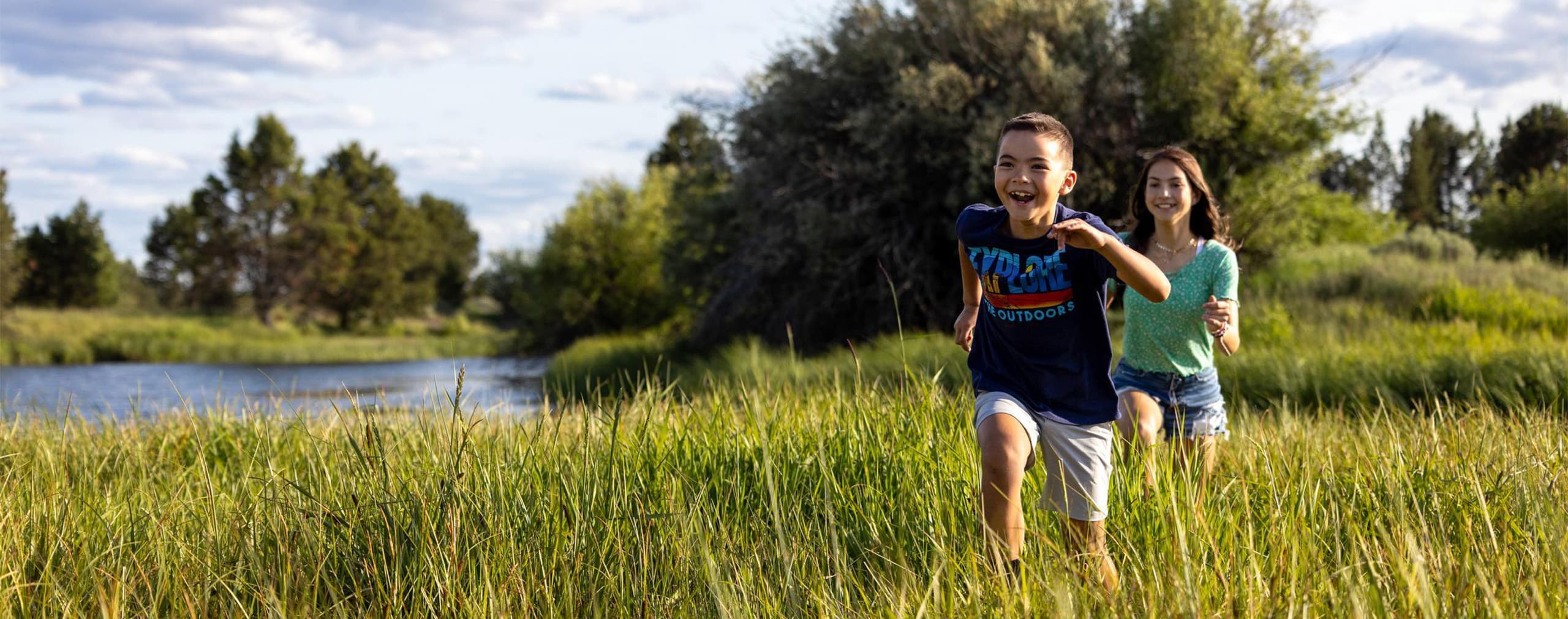 two kids running through long grass in the summer