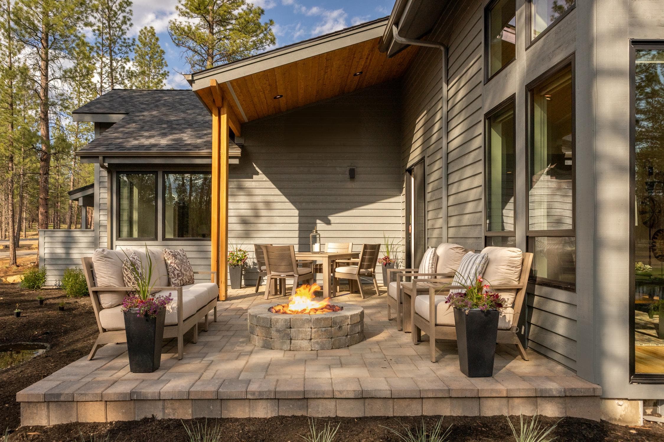 outdoor firepit with chairs surrounding it and an outdoor couch on a patio next to a house