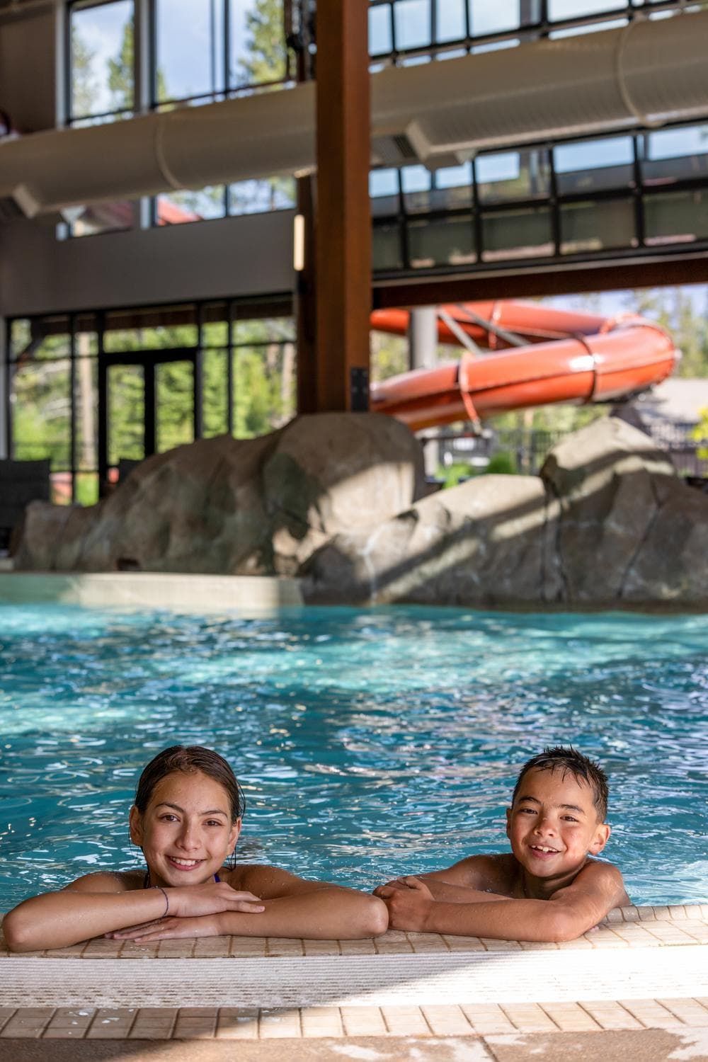 two kids sitting in the pool peaking over the edge at the Cove with the doors open letting in sunshine