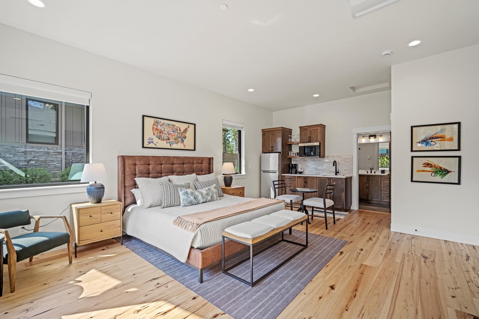 a studio bedroom unit with a king bed, kitchenette, small sitting area and wooden floors