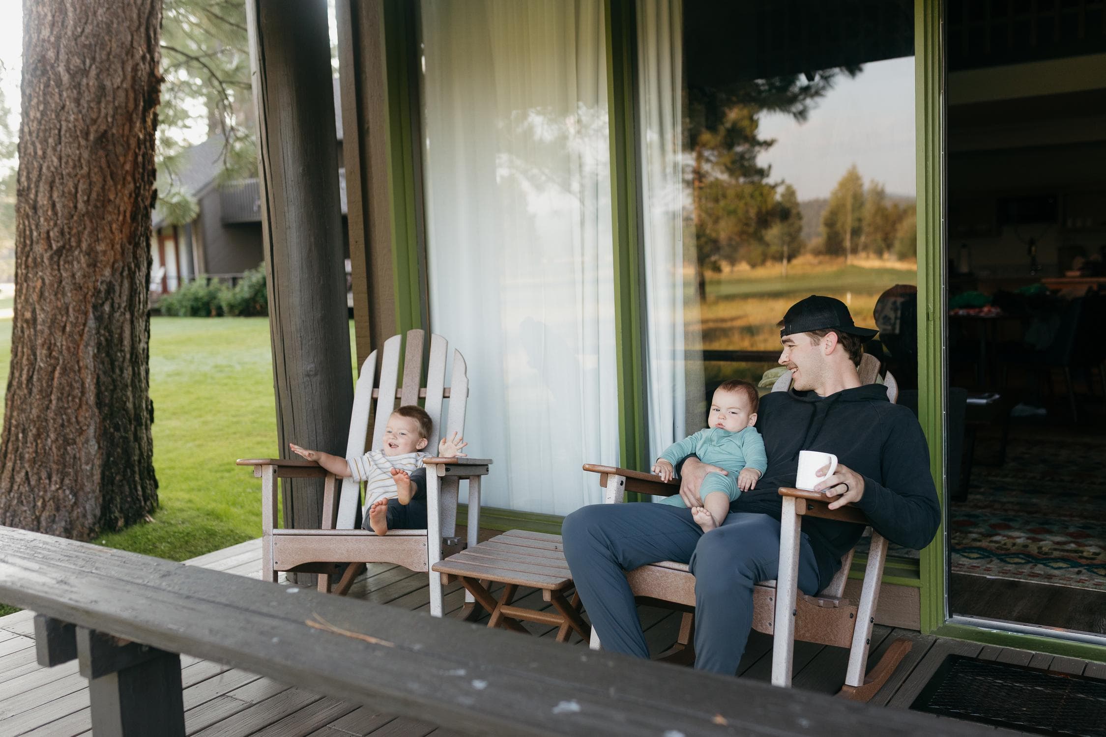 a father and his two small children sitting on a patio in a loge village guest room