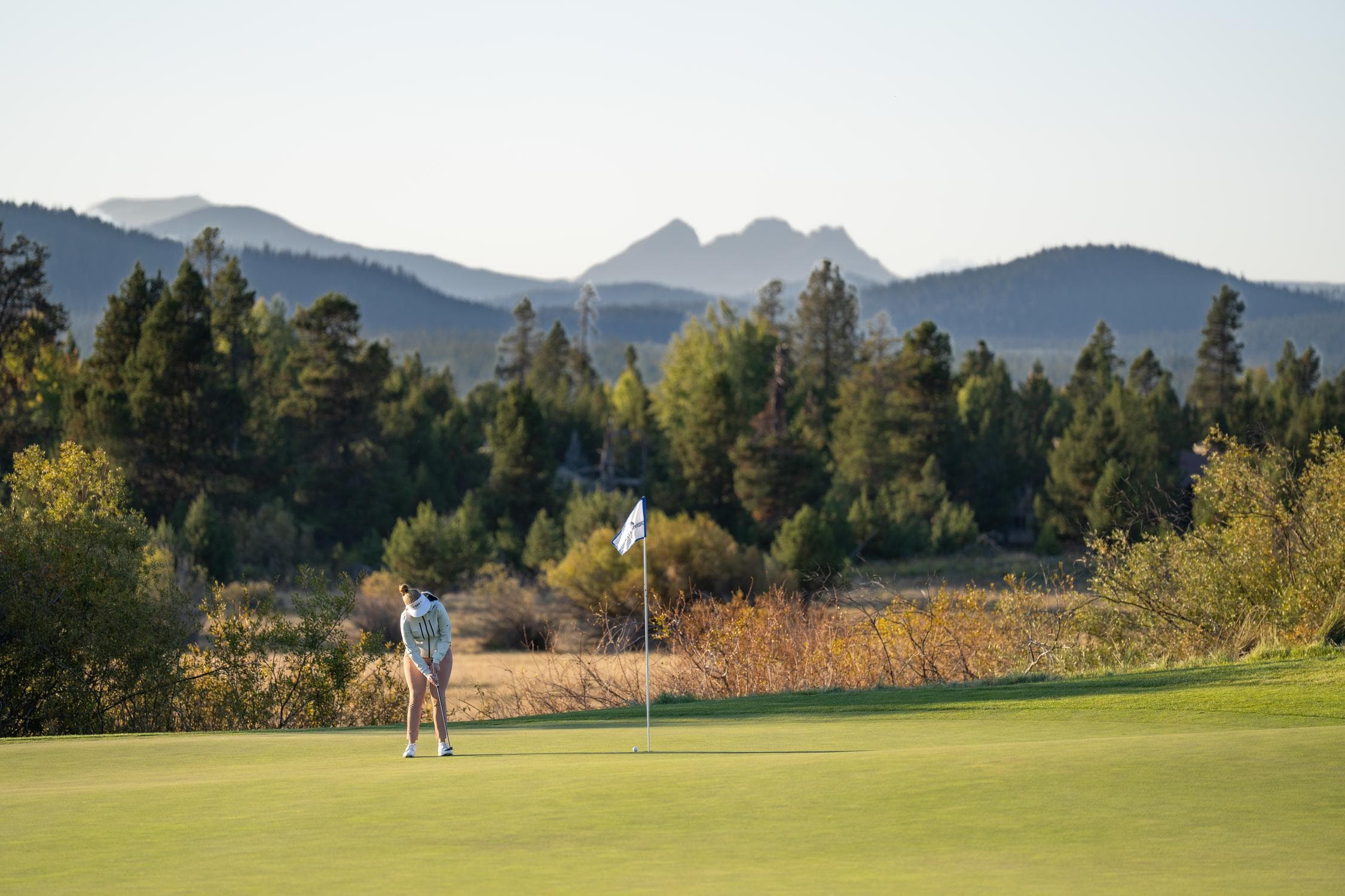 a person putting at Crosswater golf course with a mountain and rolling hills in the background